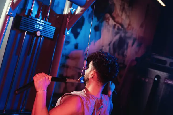 남자는 체육관의 신비한 파란색과 빨간색 사이에서 초점과 기계에 자신의 형태를 스톡 이미지