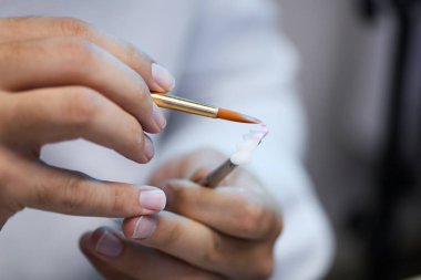 Diş protezine titizlikle porselen uygulayan bir teknisyenin ellerini kapatın. Diş laboratuarında ince detaylar için fırça kullanın.