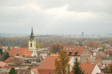 Belgrad, Sırbistan - 3 Aralık 2023: Tanınmış bir kilise kulesi ve çatılardan oluşan bir duvar halısı ile tarihi bölge üzerinde bulutlu bir gökyüzü beliriyor, eski Belgrad 'ın özünü yansıtıyor