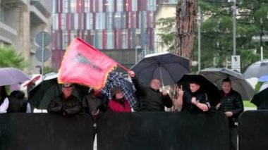 Tiran, Arnavutluk - 28 Kasım 2023: Yağmurlu bir Bağımsızlık Günü 'nde Arnavut bayrakları ve şemsiyeli vatandaşlar, Ulus Bulvarı' nın şehitleri caddesindeki geçit törenini yol kenarından izliyor