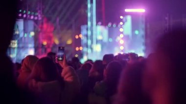 Konsere gidenler gecenin karanlığına dalmış, bulanık sahneyi telefonlarıyla kaydediyor, canlı Bokeh ışıkları arasında anıları yakalıyorlar.