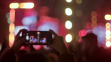 Konsere gidenler gecenin karanlığına dalmış, bulanık sahneyi telefonlarıyla kaydediyor, canlı Bokeh ışıkları arasında anıları yakalıyorlar.