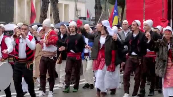 ティラナ アルバニア 2023年11月28日 国家の殉教者のアベニュー 伝統的な服装の学生や人々は熱狂的に雨の独立記念日にアルバニアの旗で行進します — ストック動画
