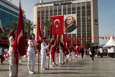 İzmir, Türkiye - 23 Nisan 2024: Cumhuriyet Meydanı 'ndaki Ulusal Egemenlik ve Çocuk Günü kutlamaları sırasında çocuklar bayraklarla hazırda bekliyor, arkada at sırtında Atatürk heykeli bulunuyor