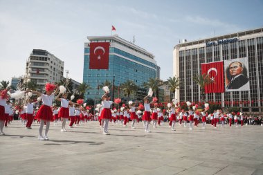 İzmir, Türkiye - 23 Nisan 2024: Kırmızılı beyazlı çocukların Ulusal Egemenlik ve Çocuk Günü boyunca arkaplanı süsleyen Türk bayrakları ve Atatrk 'ın portresiyle yaptıkları neşeli dans.