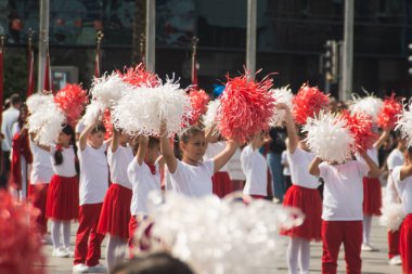 İzmir, Türkiye - 23 Nisan 2024: Türkiye 'nin Ulusal Egemenlik ve Çocuk Günü kutlamaları sırasında Cumhuriyet Meydanı' nda kırmızı ve beyaz giyinmiş çocuklar ponpon kızlarıyla neşeyle dans ediyorlar