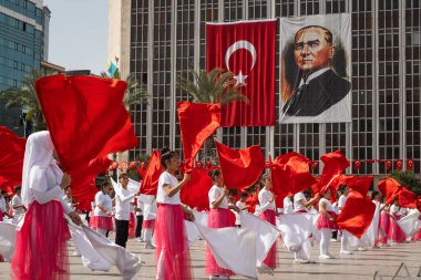 İzmir, Türkiye 23 Nisan 2024 Kırmızılı ve beyazlı çocukların Ulusal Egemenlik ve Çocuk Günü boyunca arkaplanı süsleyen Türk bayrakları ve Atatürk 'ün portresiyle yaptıkları neşeli dans.