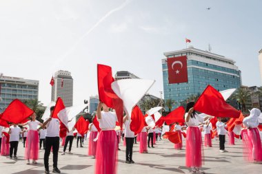 İzmir, Türkiye - 23 Nisan 2024: Kırmızılı ve beyazlı genç öğrenciler, Türkiye 'nin Ulusal Egemenlik ve Çocuk Günü kutlamaları sırasında İzmir Cumhuriyet Meydanı' nda bayrak dansı yaptılar