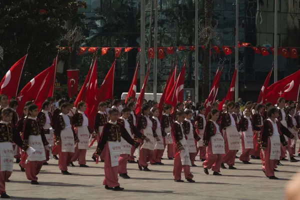 İzmir, Türkiye - 23 Nisan 2024: Geleneksel Türk kıyafetleri içindeki öğrenciler, Atatürk 'ün portresi ve Türk bayrağının arkaplanıyla Ulusal Egemenlik ve Çocuk Günü kutlamalarında kültür dansı yaptılar