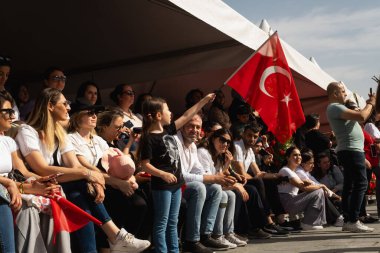 İzmir, Türkiye - 23 Nisan 2024: Cumhuriyet Meydanı 'nda Ulusal Egemenlik ve Çocuk Günü kutlamaları sırasında elinde Türk bayrakları bulunan seyirciler.