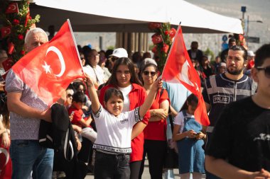 İzmir, Türkiye - 23 Nisan 2024: Cumhuriyet Meydanı 'nda Ulusal Egemenlik ve Çocuk Günü kutlamaları sırasında elinde Türk bayrakları bulunan seyirciler.