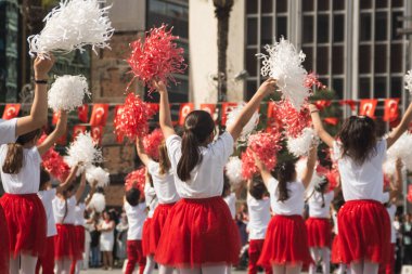İzmir, Türkiye - 23 Nisan 2024: Türkiye 'nin Ulusal Egemenlik ve Çocuk Günü kutlamaları sırasında Cumhuriyet Meydanı' nda kırmızı ve beyaz giyinmiş çocuklar ponpon kızlarıyla neşeyle dans ediyorlar
