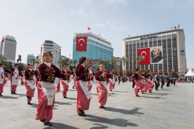 İzmir, Türkiye - 23 Nisan 2024: Geleneksel Türk kıyafetleri içindeki öğrenciler, Atatürk 'ün portresi ve Türk bayrağının arkaplanıyla Ulusal Egemenlik ve Çocuk Günü kutlamalarında kültür dansı yaptılar