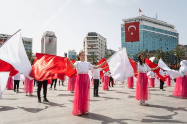 İzmir, Türkiye - 23 Nisan 2024: Kırmızılı ve beyazlı genç öğrenciler, Türkiye 'nin Ulusal Egemenlik ve Çocuk Günü kutlamaları sırasında İzmir Cumhuriyet Meydanı' nda bayrak dansı yaptılar