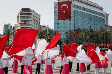 İzmir, Türkiye - 23 Nisan 2024: Kırmızılı ve beyazlı genç öğrenciler, Türkiye 'nin Ulusal Egemenlik ve Çocuk Günü kutlamaları sırasında İzmir Cumhuriyet Meydanı' nda bayrak dansı yaptılar