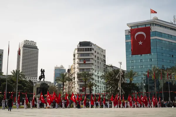 İzmir, Türkiye - 23 Nisan 2024: Cumhuriyet Meydanı 'ndaki Ulusal Egemenlik ve Çocuk Günü kutlamaları sırasında çocuklar bayraklarla hazırda bekliyor, arkada at sırtında Atatürk heykeli bulunuyor