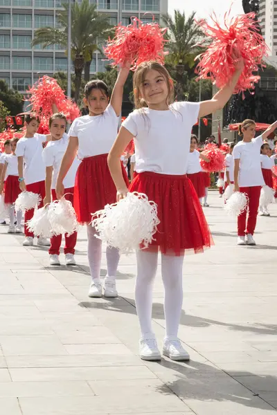 İzmir, Türkiye - 23 Nisan 2024: Türkiye 'nin Ulusal Egemenlik ve Çocuk Günü kutlamaları sırasında Cumhuriyet Meydanı' nda kırmızı ve beyaz giyinmiş çocuklar ponpon kızlarıyla neşeyle dans ediyorlar