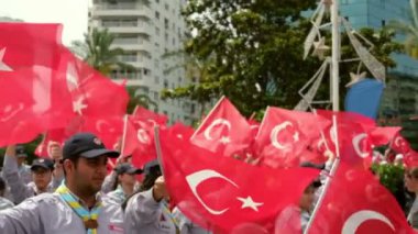 İzmir, Türkiye - 19 Mayıs 2024: Cumhuriyet Meydanı 'nda düzenlenen Gençlik ve Spor Günü ve Atatürk Anma Günü kutlamaları sırasında Türk bayraklarını ağır çekimde sallayan izcilerin yakın çekim videosu
