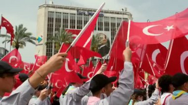 İzmir, Türkiye - 19 Mayıs 2024: Cumhuriyet Meydanı 'nda düzenlenen Gençlik ve Spor Günü ve Atatürk Anma Günü kutlamaları sırasında Türk bayraklarını ağır çekimde sallayan izcilerin yakın çekim videosu