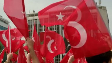 İzmir, Türkiye - 19 Mayıs 2024: Cumhuriyet Meydanı 'nda düzenlenen Gençlik ve Spor Günü ve Atatürk Anma Günü kutlamaları sırasında Türk bayraklarını ağır çekimde sallayan öğrencilerin yakın çekim videosu
