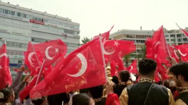 İzmir, Türkiye - 19 Mayıs 2024: Cumhuriyet Meydanı 'nda düzenlenen Gençlik ve Spor Günü ve Atatürk Anma Günü kutlamaları sırasında Türk bayraklarını ağır çekimde sallayan öğrencilerin yakın çekim videosu