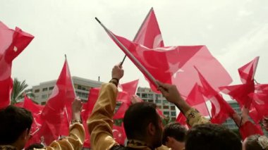 İzmir, Türkiye - 19 Mayıs 2024: Cumhuriyet Meydanı 'nda düzenlenen Gençlik ve Spor Günü ve Atatürk Anma Günü kutlamaları sırasında Türk bayraklarını ağır çekimde sallayan öğrencilerin yakın çekim videosu