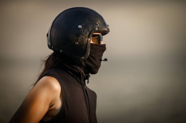 Portrait of a biker wearing a leather helmet, goggles, and a face covering, ready for the ride. The rider is dressed in black, giving a tough and mysterious appearance clipart