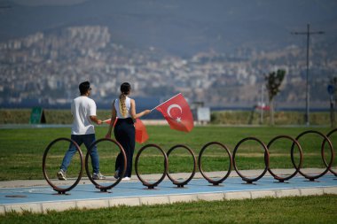 İzmir, Türkiye - 30 Ağustos 2024: Bir erkek ve bir kadın, Zafer Günü kutlamalarında Türk bayrağıyla birlikte yürüyor, ulusal gurur ve birliği simgeliyor.