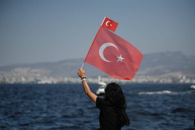 İzmir, Türkiye - 30 Ağustos 2024: Bir kadın, liman yakınlarında düzenlenen Zafer Günü kutlamalarını izlerken, ulusal gurur ruhunu yansıtıyor