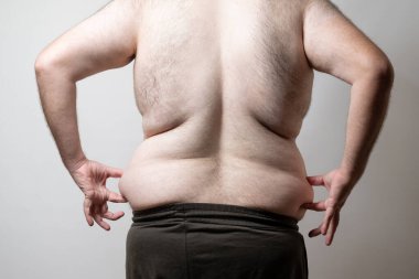 Rear view of an overweight man showing his back, with his hands pinching the fat on his sides. The image highlights body fat, skin folds, and natural texture. clipart