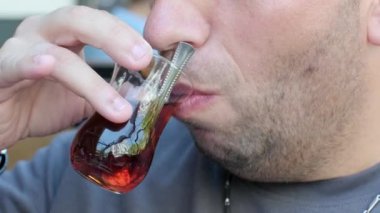 Geleneksel bardaktan sıcak çay yudumlayan bir adamın yakın çekim videosu. Video, kültürel çay deneyimini gözler önüne seren nazik yudumlamaya odaklanıyor.
