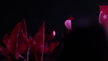 İzmir, Türkiye - 29 Ekim 2024: Cumhuriyet Günü kutlamaları için Gndodu Meydanı 'nda düzenlenen ücretsiz bir konser sırasında, insanlar Türk bayraklarını sallıyor ve festival atmosferinin keyfini çıkarıyorlar. Ağır çekimde yakalandı.