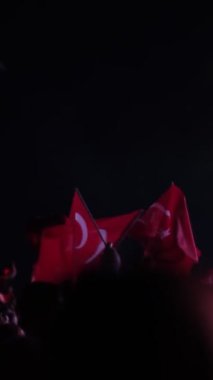 İzmir, Türkiye - 29 Ekim 2024: Cumhuriyet Günü kutlamaları için Gndodu Meydanı 'nda düzenlenen ücretsiz bir konser sırasında, insanlar Türk bayraklarını sallıyor ve festival atmosferinin keyfini çıkarıyorlar. Ağır çekimde yakalandı.