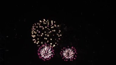 Gece gökyüzüne karşı parlak renk patlamaları gösteren nefes kesici bir havai fişek gösterisinin yavaş çekim videosu büyüleyici bir kutlama atmosferi yaratıyor.