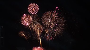 Gece gökyüzüne karşı parlak renk patlamaları gösteren nefes kesici bir havai fişek gösterisinin yavaş çekim videosu büyüleyici bir kutlama atmosferi yaratıyor.