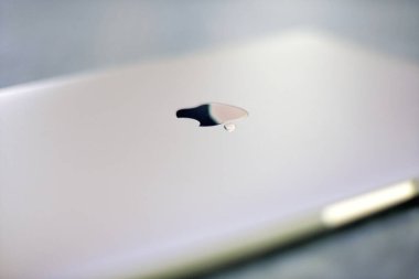 İzmir, Türkiye - 11 Eylül 2024: Apple MacBook dizüstü bilgisayarının sığ bir alan derinliğine sahip, Apple logosuna odaklanmış, bulanık, atmosferik bir arkaplan yaratıyor