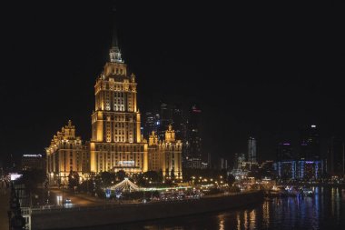 Moskova, Rusya - 20 Ağustos 2024: Moskova 'daki Ukrayna Oteli' nin gece çekilmiş bir fotoğrafı, karanlık gökyüzüne karşı aydınlanan klasik Stalinist gökdelen, mimari zarafetini vurguluyor