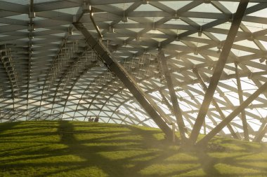 Moskova, Rusya - 16 Ağustos 2024: Moskova 'daki Zaryadye Parkı' nın yenilikçi cam tepe örtüsü ve güneş ışığıyla yıkanan yeşil tepesi modern şehir tasarımını yansıtıyor.