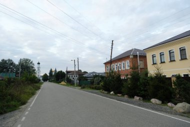 Moskova, Rusya - 20 Ağustos 2024: Ashitkovo köyünde sakin bir cadde, ağaçlı ve açık gökyüzü olan geleneksel Rus mimarisini gözler önüne seriyor