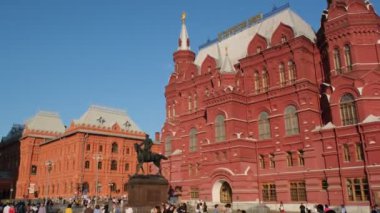 Moskova, Rusya - 16 Ağustos 2024: Moskova Tarih Müzesi ve bir anıtı yakalayan bir video, ziyaretçiler açık mavi gökyüzünün altında ön planda yürüyor