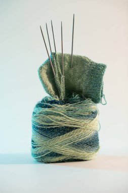 A detailed close-up of a green knitting project on a spool of yarn with knitting needles, set against a plain white background, emphasizing intricate details and creativity clipart