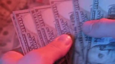 100 dolarlık banknotları sayan, dinamik ve canlı bir ortamda banknotların detaylarını gösteren, finans ve para birimlerine odaklı ellerin yakın plan videosu.