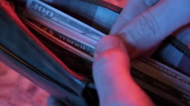 Birkaç yüz dolarlık banknotların boş bir cüzdana konduğu, zenginliği, mali yönetimi ve tasarruf ve para yönetimi kavramını temsil eden yakın plan bir video.