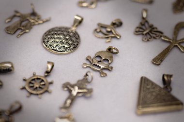 Diğer benzersiz şekillerle birlikte bir kafatası tasarımı içeren gümüş kolye koleksiyonu.