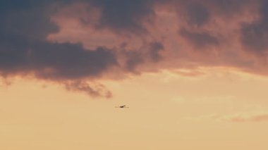 Flamingoların nefes kesici yavaş çekim videosu canlı bir günbatımı gökyüzünde zarifçe uçarak barışı ve doğal güzelliği çağrıştırıyor.