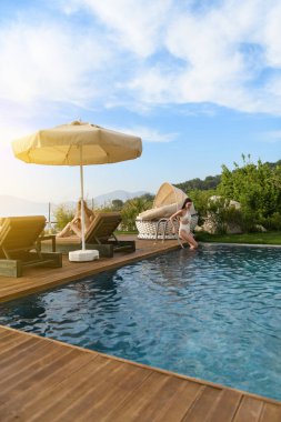 20 'li yaşlarda esmer ve sarışın bir kadın otel odasının özel havuzunda birlikte rahatlar ve lüks bir kaçamağın tadını çıkarırlar..