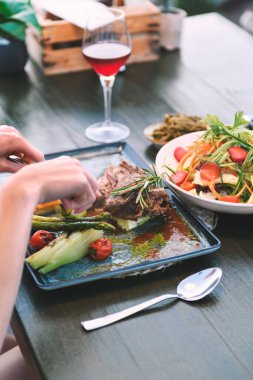 20 'li yaşlarda bir kadının, lüks bir otel restoranında et kesmek için çatal bıçak kullanırken çekilmiş yakın plan fotoğrafı..