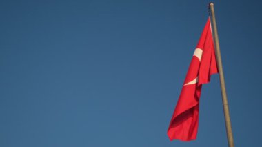 Türk bayrağının görkemli yavaş çekim görüntüleri rüzgarda zarif bir şekilde dalgalanırken güzel mavi bir arka plana doğru