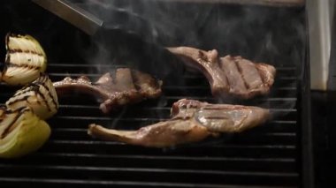 Yavaş çekimde, ağız sulandırıcı suları ve çıtır çıtır kenarları olan ızgara kuzu pirzolası.