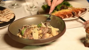 Lüks otel havuz başında ağır çekimde çatalla tavuk yemeğinin tadını çıkaran zarif bir kadın.